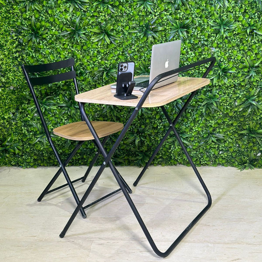 Foldable table with two chairs against a green leafy wall